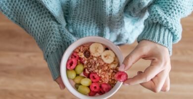 person holding white ceramic bowl with red and yellow beans